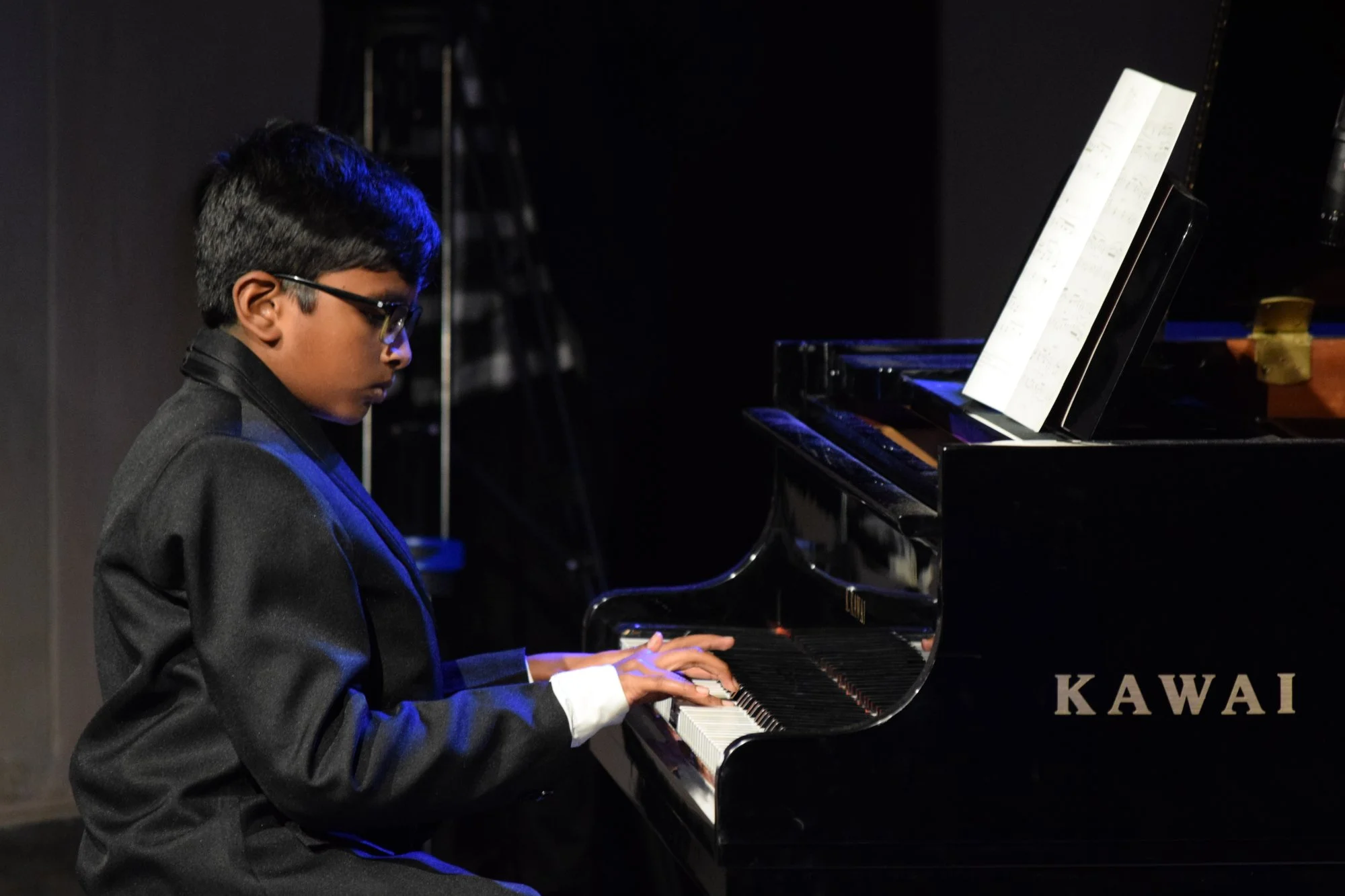 Young boy piano student performing on Kawai grand