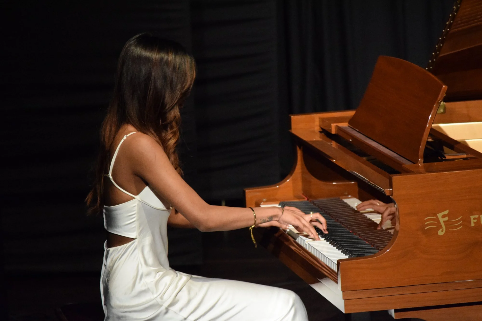 Female piano student performing on Furtados grand piano at annual recital