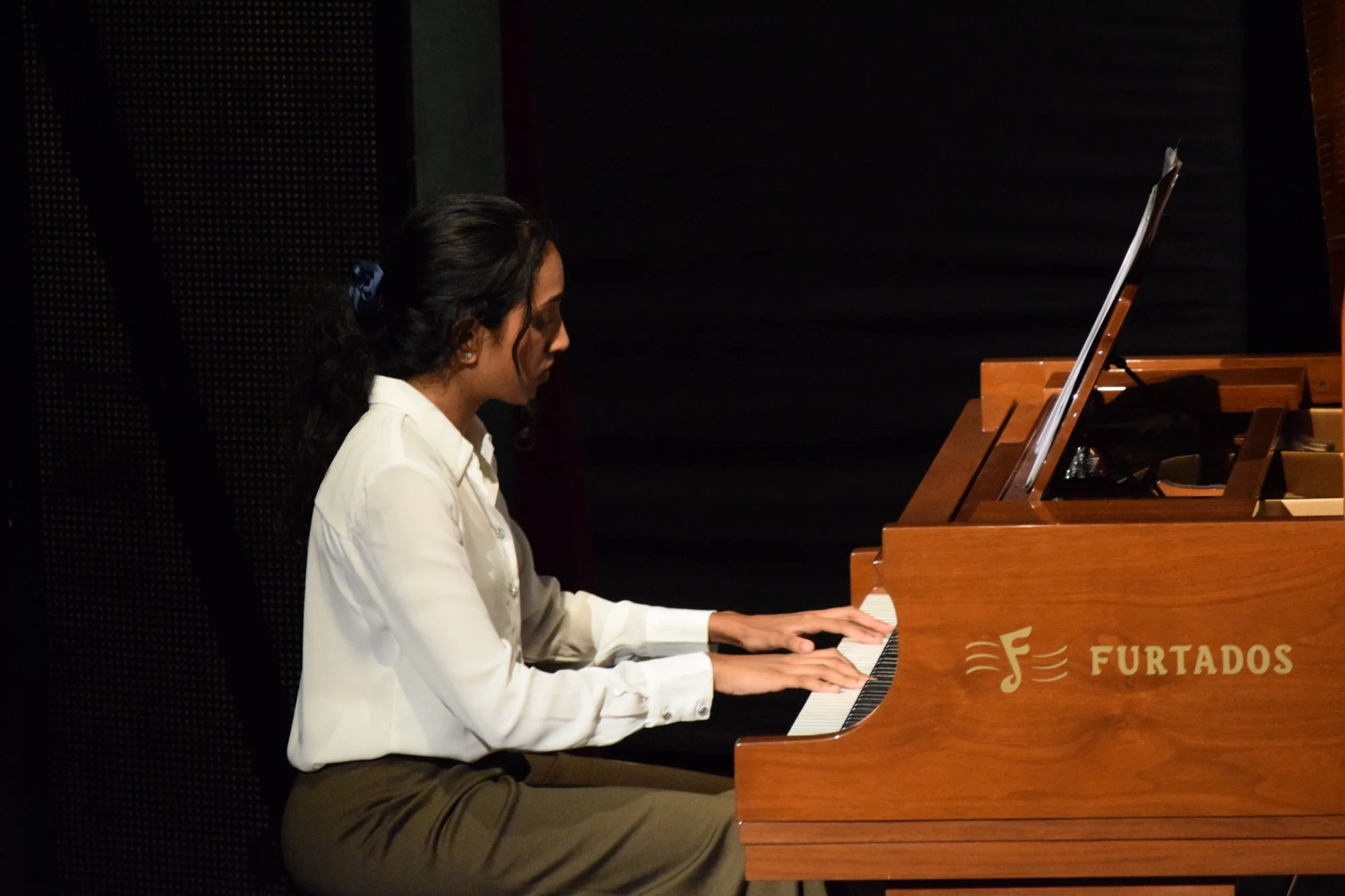 Female piano student performing on Furtados grand piano at annual recital