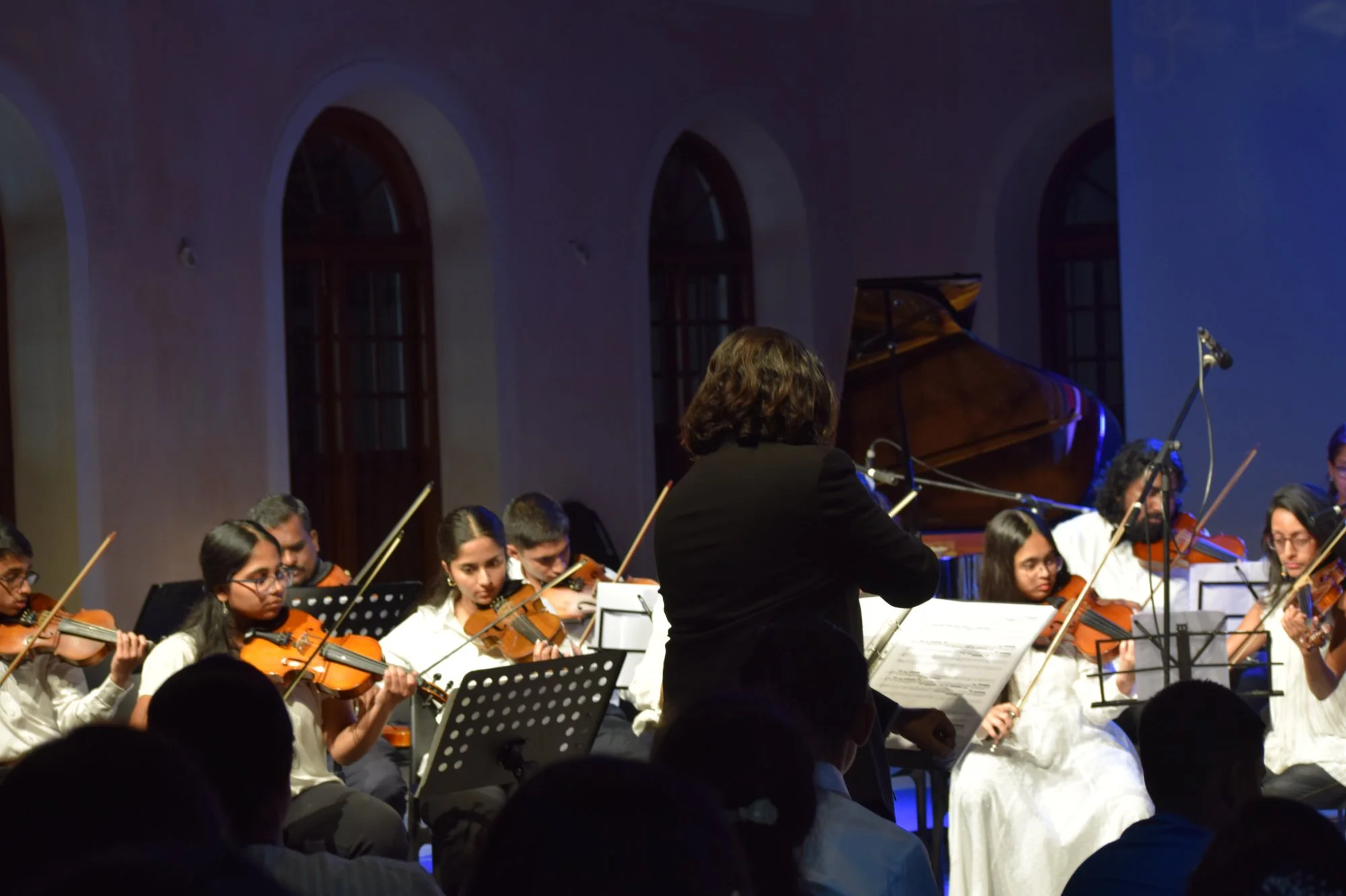 FSG violin students with full orchestra and conductor at annual recital